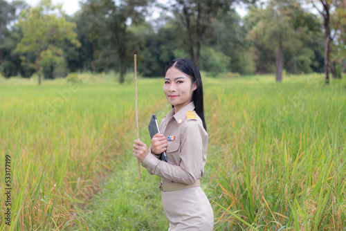 Beautiful Thai teacher with tablet computer in rice field.