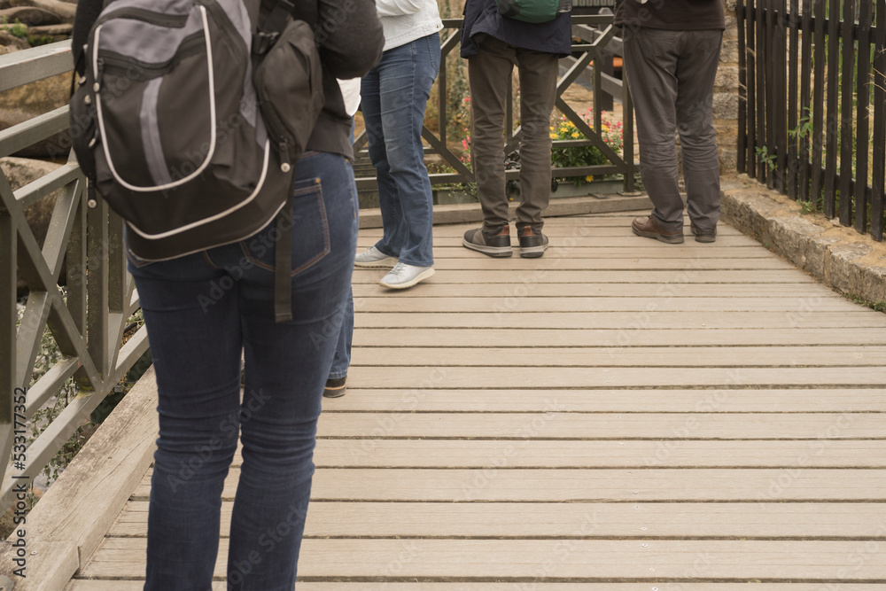 Tourist legs with shoes in front of a railing on wooden floor rear view on tourist with backpack Tourist legs with shoes in front of a railing on wooden floor rear view on tourist with backpack