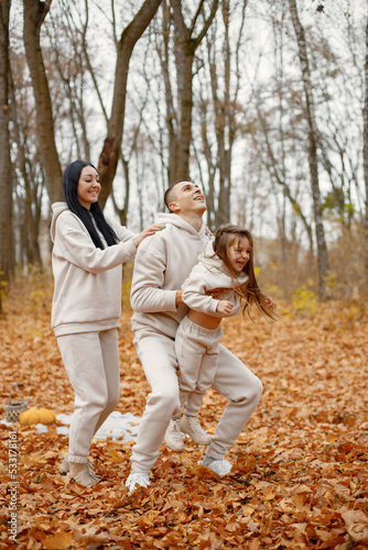 Young family playing in autumn forest and throwing a daughter in the air © prostooleh