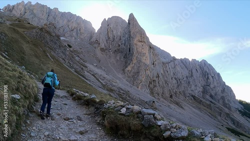 Rear view of woman with backpack on hiking trail surrounded by massive steep mountain peaks in Hochschwab Alps, Upper Styria, Austria, Europe. Hiking route through Foelzklamm to Foelzstein, Foelzkogel photo