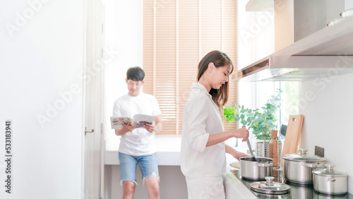 happy asian couple cooking healthy food. family man read cook book recipe support delightful wife making lunch or dinner. beautiful attractive girlfriend preparing healthy meal with cheerful husband