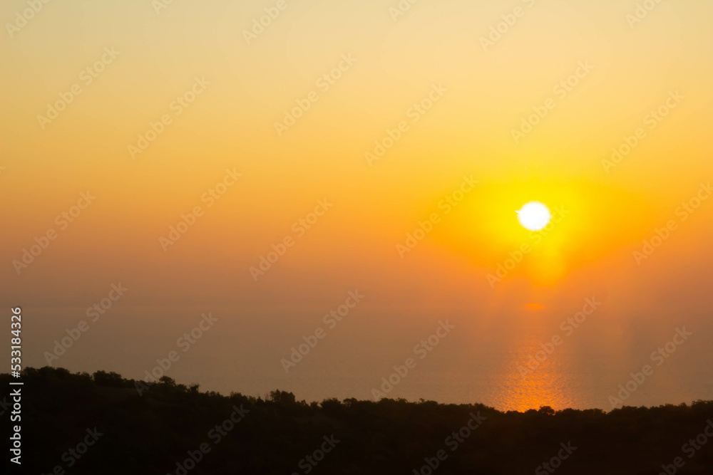 Beautiful view of Sunrise on the sea with Mountains and orange color sky.