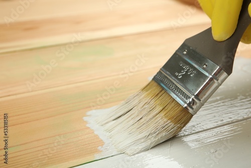 Fototapeta Naklejka Na Ścianę i Meble -  Worker applying white paint onto wooden surface, closeup. Space for text