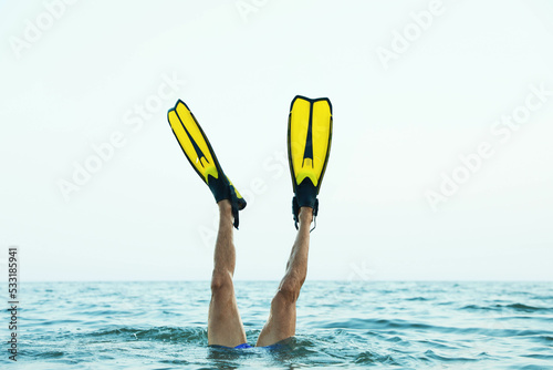 Man in flippers diving into sea water, closeup