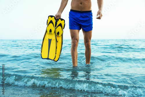 Man with flippers walking out of sea water, closeup