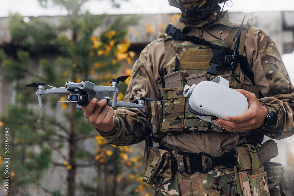 Soldier engineer holds an FPV quadrocopter and glasses view in hands. Concept military use of aerial drone in army Soldier engineer holds an FPV quadrocopter and glasses view in hands. Concept military use of aerial drone in army