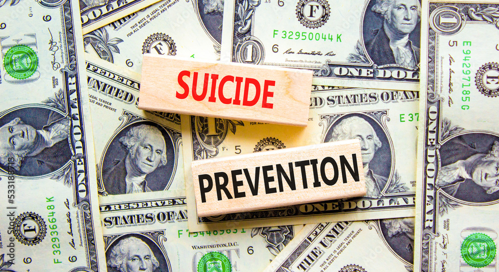 Suicide prevention symbol. Concept words Suicide prevention on wooden blocks. Beautiful background from dollar bills. Psychological and suicide prevention concept. Copy space.