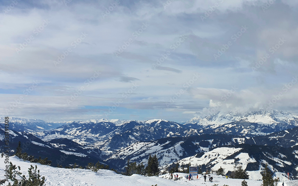 Panorama of the snow-capped Alps and view of the ski runs of Flachau in Austria from the Griessenkareck summit on a cloudy winter day.