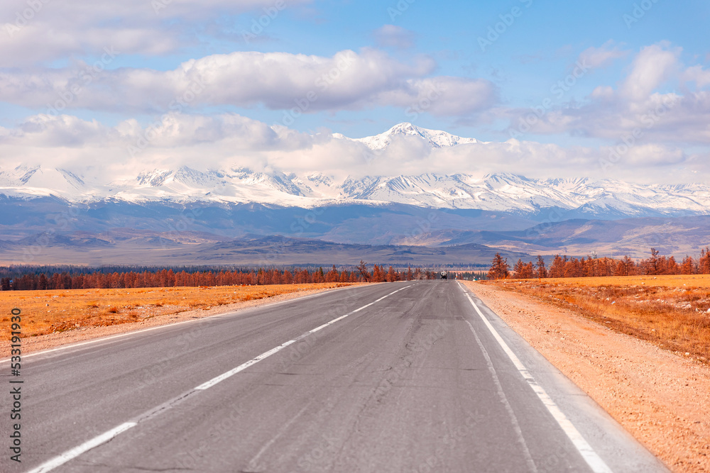 Beautiful landscape road in autumn forest with snow peaks mountains Chuysky tract, Altai Kurai steppe Russia.
