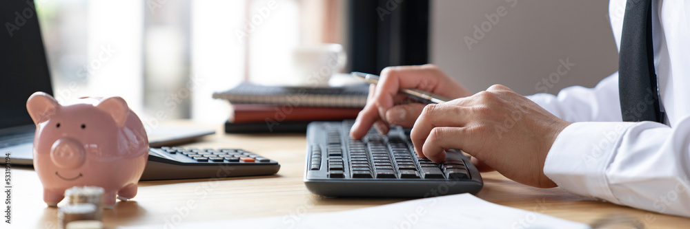 Banking and savings finance concept, close-up of businessman's hands pressing keyboard keys and fill out the documents for tax refund and tax savings Banking and savings finance concept, close-up of businessman's hands pressing keyboard keys and fill out the documents for tax refund and tax savings