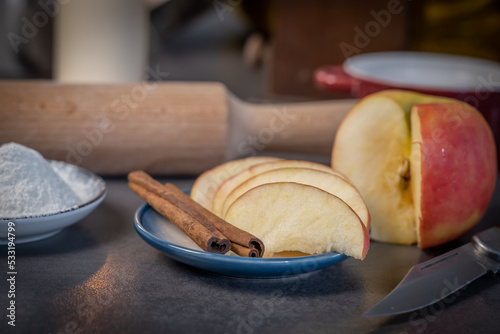 cannelle et pomme coupée dans une soucoupe pour préparation de gateau de fête avec un décoration en fond flou photo