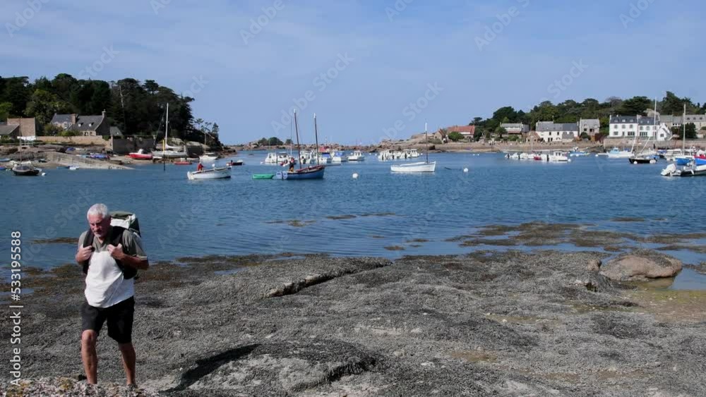 Un randonneur qui regarde les bateaux dans le port de Ploumanach en Bretagne - France - 4K