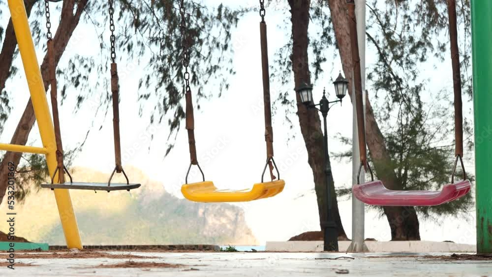 4K. The swings in the playground are swinging. without children sitting. Empty swing in