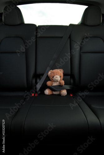 Teddy Bear in backseat of electric car with seatbelt on close up