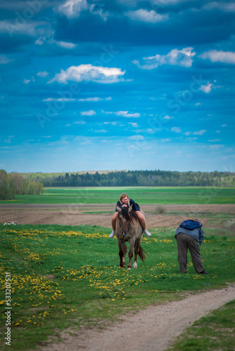A young beautiful blonde girl trains a horse in the field. © shymar27