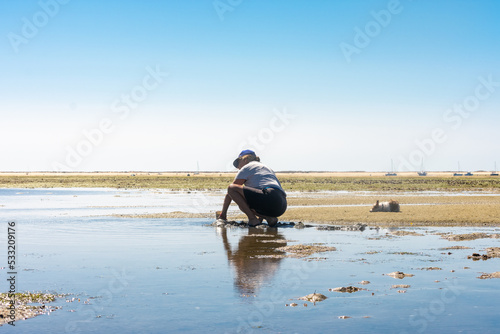 woman working with coquillage picking at sand and sea landcape in portugal