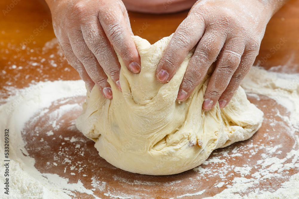 The hands of a Jewish woman knead the dough for wicker challahs for the holiday on the table. - obrazy, fototapety, plakaty 