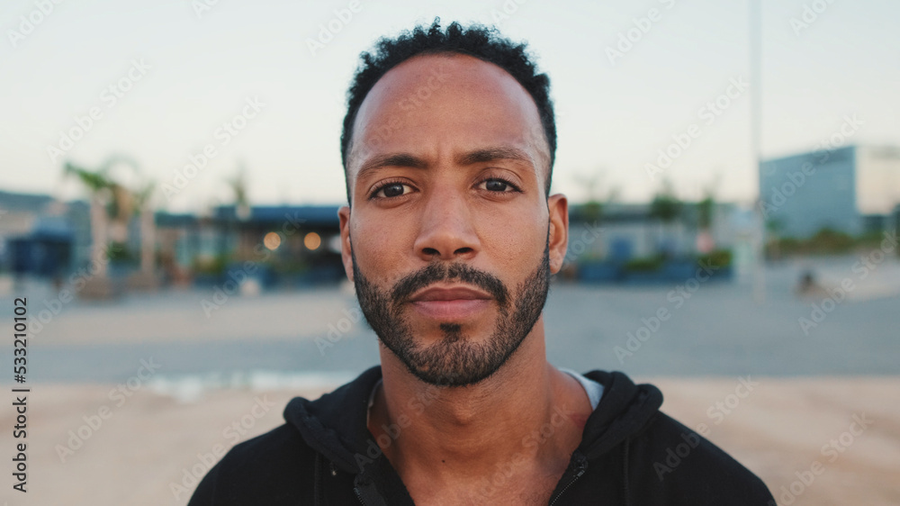 Close-up, young bearded male athlete standing on the embankment, looking at the sea. Guy turns his head and looks at the camera. Close-up, young bearded male athlete standing on the embankment, looking at the sea. Guy turns his head and looks at the camera.