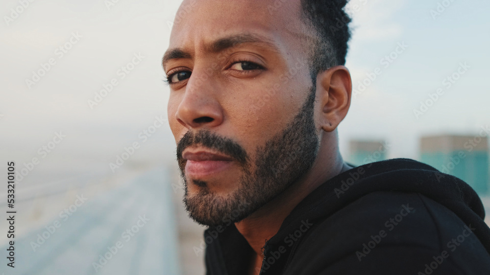 Close-up, young bearded male athlete standing on the embankment, looking at the sea. Guy turns his head and looks at the camera. Close-up, young bearded male athlete standing on the embankment, looking at the sea. Guy turns his head and looks at the camera.