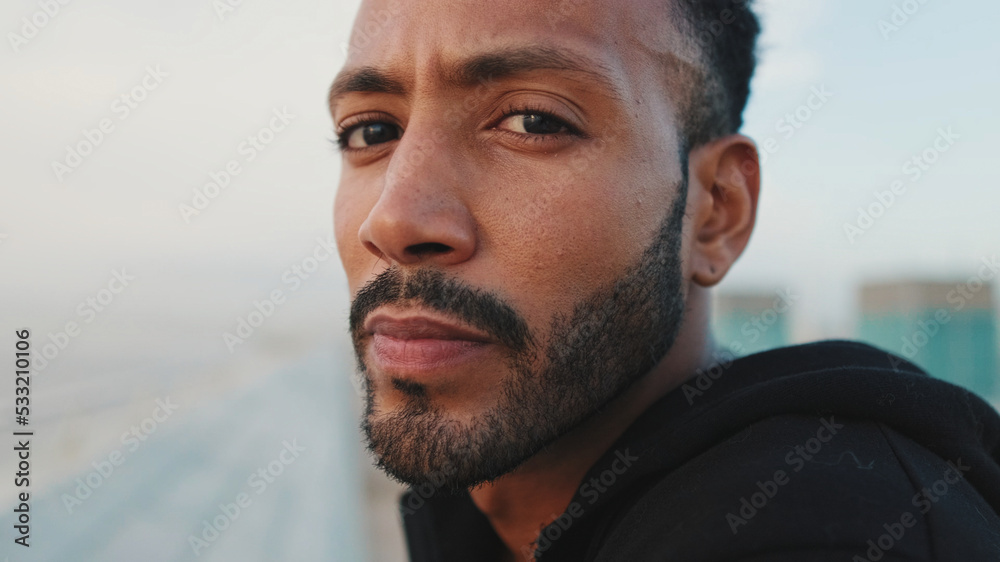 Close-up, young bearded male athlete standing on the embankment, looking at the sea. Guy turns his head and looks at the camera. Close-up, young bearded male athlete standing on the embankment, looking at the sea. Guy turns his head and looks at the camera.