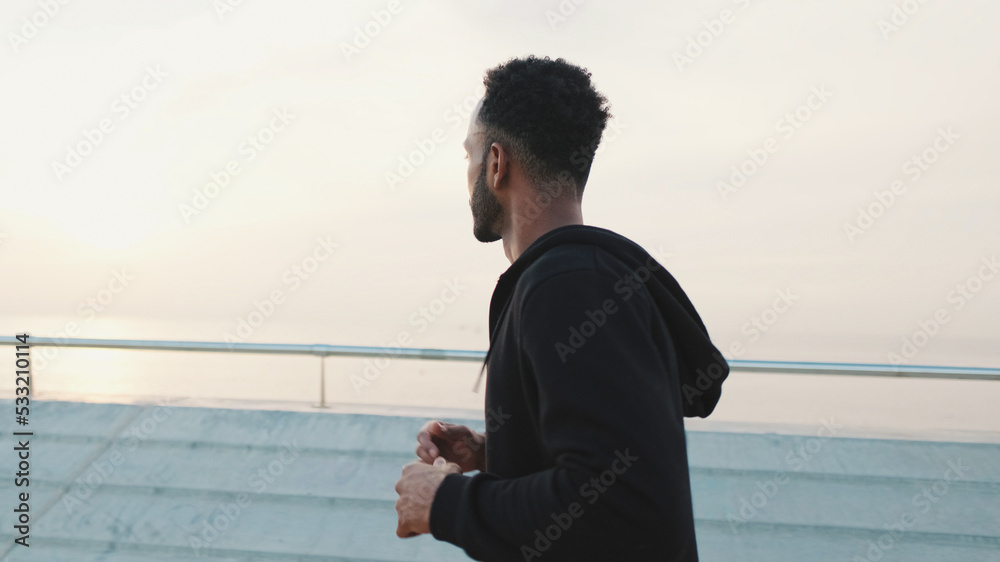 Young bearded male athlete runs along the promenade Young bearded male athlete runs along the promenade