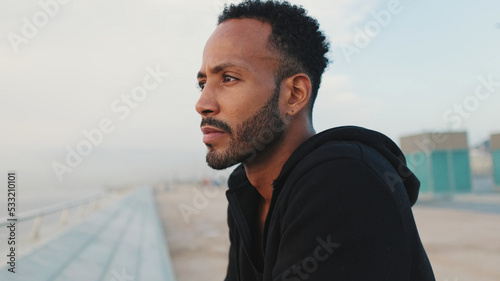 Print op canvas Close-up, young bearded male athlete standing on the embankment, looking at the sea