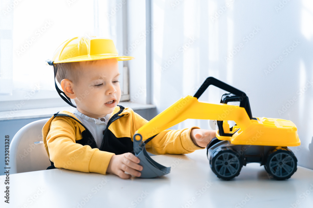 Boy with digger. Child play with excavator at home, dreams to be an engineer. Little builder. Education, and imagination, purposefulness concept Boy with digger. Child play with excavator at home, dreams to be an engineer. Little builder. Education, and imagination, purposefulness concept