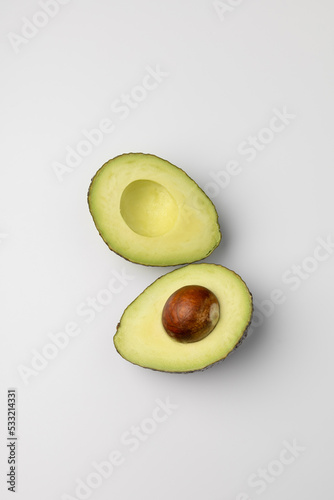 Two halves of fresh avocado on white background