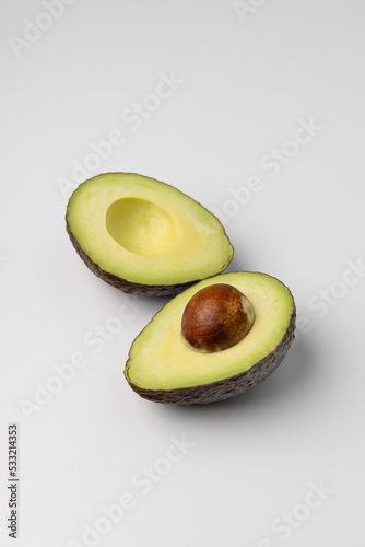 Two halves of fresh avocado on white background