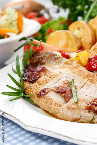 Joint of pork with baked potatoes and fresh vegetables