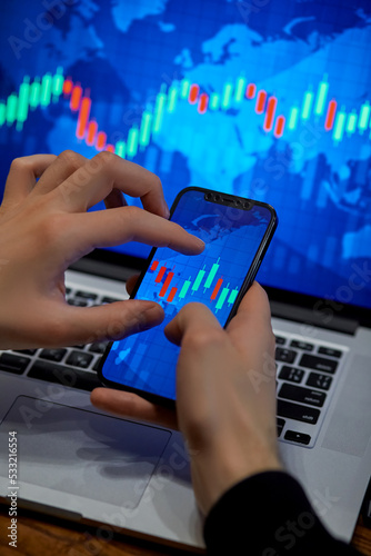 Trading. Businessman investor analyst using mobile phone analytics to analyze cryptocurrency financial market, trade data index chart graph on smartphone and laptop screen. close up