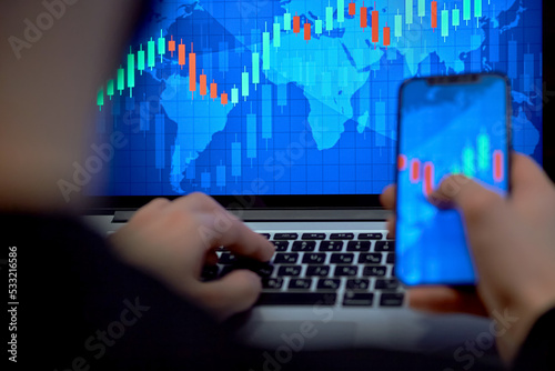 Trading. Businessman investor analyst using mobile phone analytics to analyze cryptocurrency financial market, trade data index chart graph on smartphone and laptop screen. close up