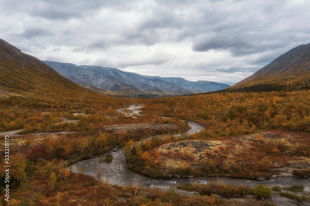 Golden autumn in the north, beyond the Arctic Circle, view of river, forest and mountains from the top.