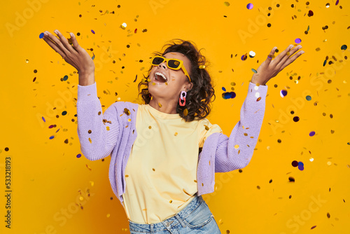 Schilderij op canvas Beautiful African woman throwing confetti and smiling against yellow background