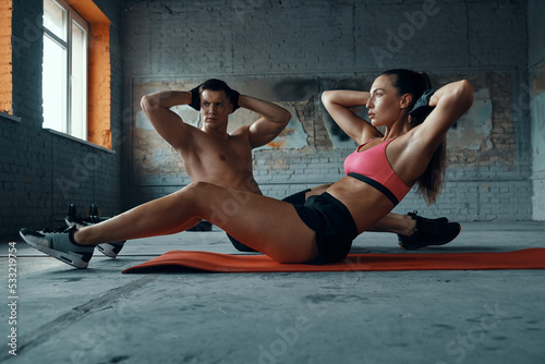 Confident fit couple exercising on exercise mats in gym together