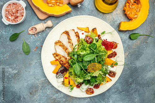 keto meal fresh salad with grilled chicken fillet, feta cheese, caramelized pumpkin, superfood concept. Healthy, clean eating, place for text, top view