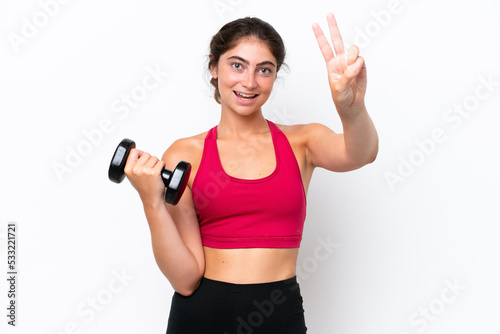 Young sport caucasian woman making weightlifting isolated on white background smiling and showing victory sign