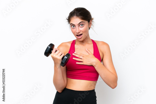 Young sport caucasian woman making weightlifting isolated on white background surprised and shocked while looking right