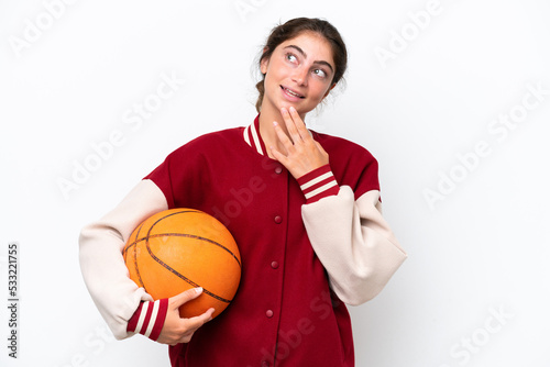Young basketball player woman isolated on white background looking up while smiling © luismolinero