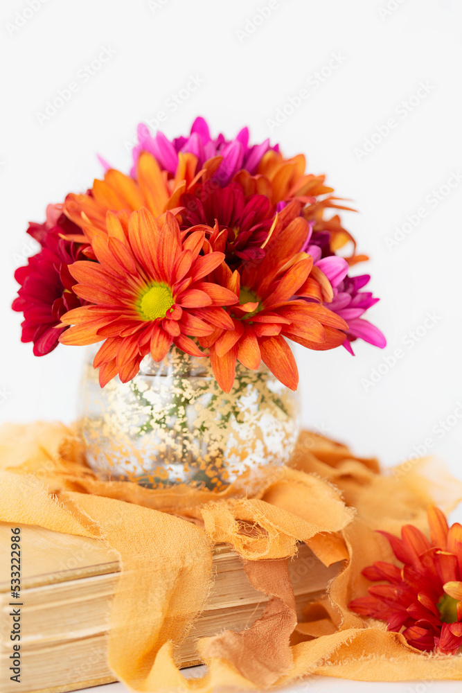 Bouquet of orange, purple, and red chrysanthemums in gold vase