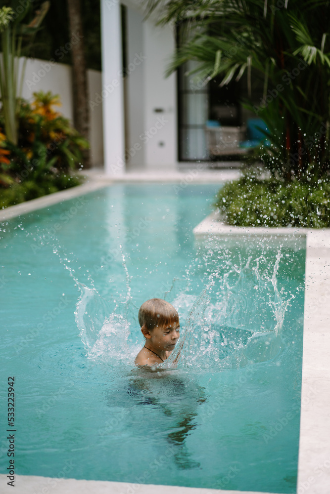 Child boy swims in the pool, jumps into the water.