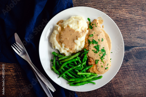 Chicken Breast Served with Green Beans, Mashed Potatoes, and Garlic Gravy: Chicken cutlet topped with creamy garlic sauce served with vegetables