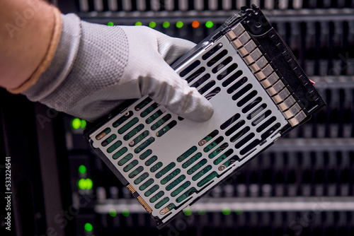 A hard disk for a raid in the hands of a man at a data storage server, close-up photo