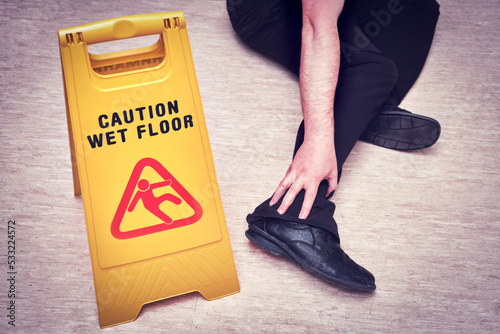 Falls and injuries on the wet floor. The sign on the plate with the text - caution wet floor