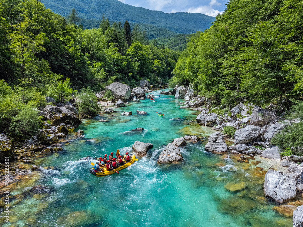 Soca Valley, Slovenia - Aerial view of the emerald alpine river Soca with rafting boats going down the river on a bright sunny summer day with green foliage. Whitewater rafting in Slovenia