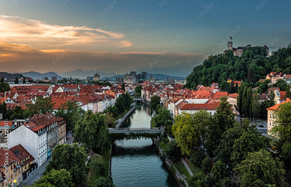 Fototapeta premium Ljubljana, Slovenia - Aerial view of Ljubljana on a summer afternoon with Ljubljanica river, Ljubljana Castle (Ljubljanski grad), skyline of the capital of Slovenia and colorful sunset sky