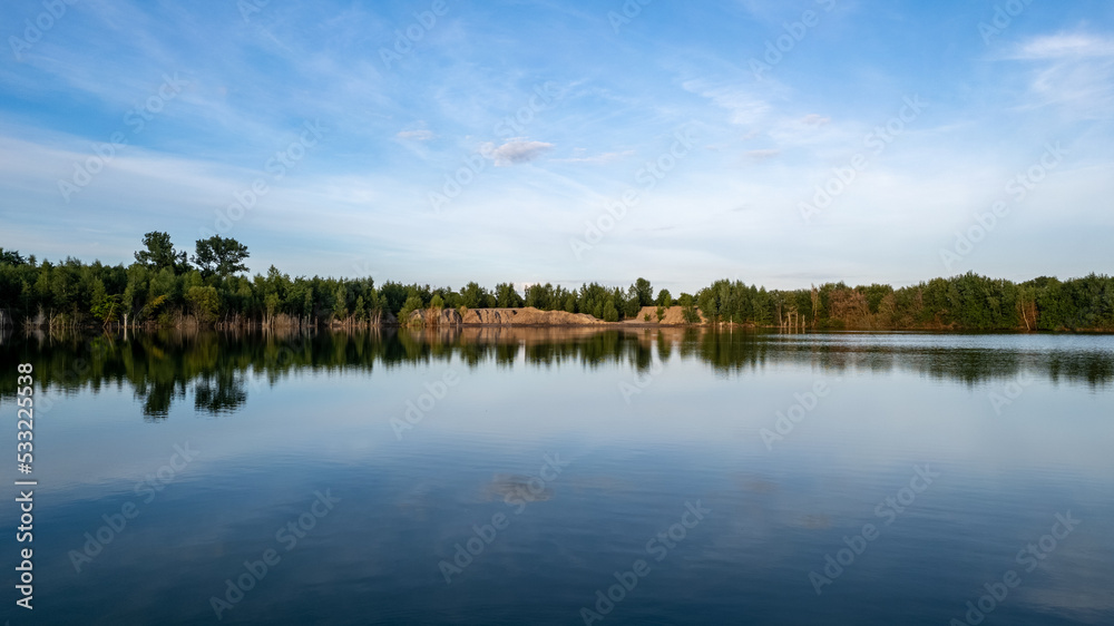 Cold summer morning in the forest with lake, forest reflection and sunset or sunrise on the water surface. High quality photo