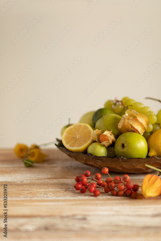 Still life:various assorted fruits (grape, apple, pear,lemon, lime,rowan, physalis) copper plate,isolated on the wooden table background with soft shadow,healthy fresh organic food.Vertical,copy space Still life:various assorted fruits (grape, apple, pear,lemon, lime,rowan, physalis) copper plate,isolated on the wooden table background with soft shadow,healthy fresh organic food.Vertical,copy space