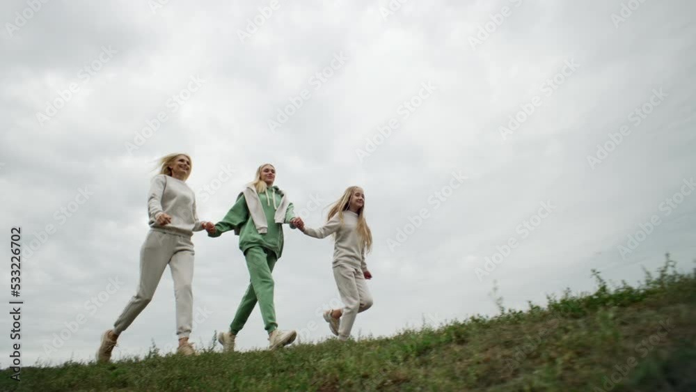 Three generations of women run across the grass. Video concept of freedom, family happiness, warmth and love of parents for children and grandchildren. High quality 4k footage Three generations of women run across the grass. Video concept of freedom, family happiness, warmth and love of parents for children and grandchildren. High quality 4k footage
