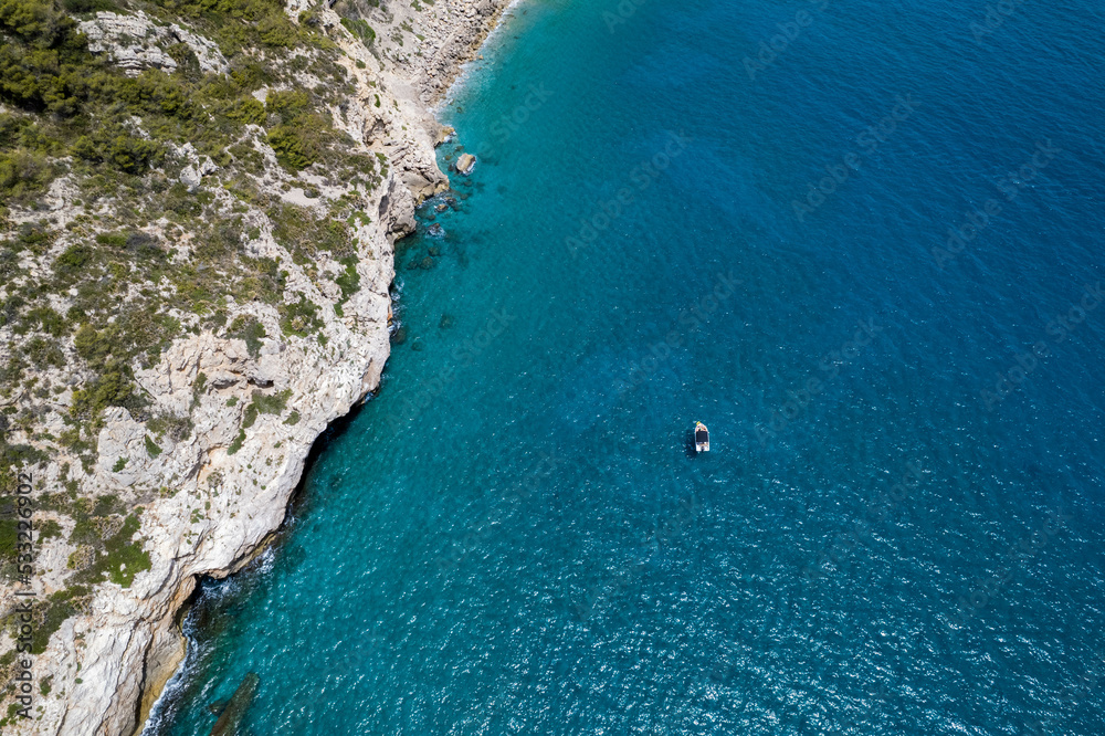 drone view between of a mediterranean sea and a coastline with a boat into the sea